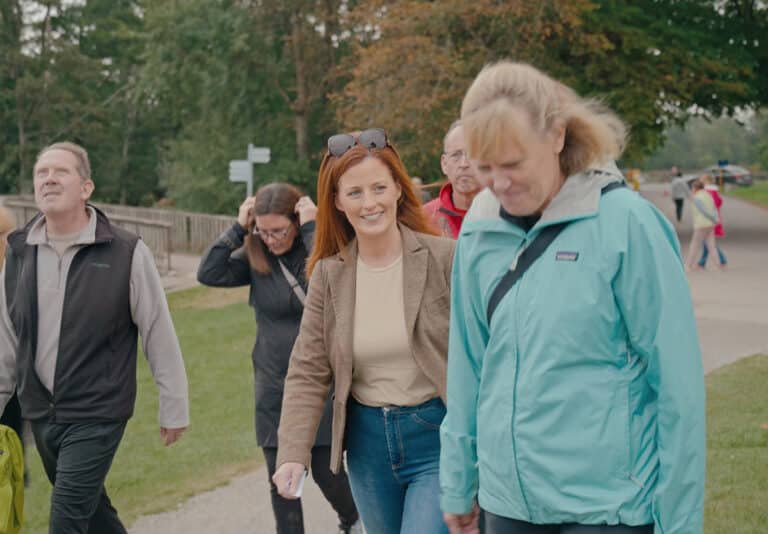 Group of people walking outdoors, smiling and enjoying a park setting.