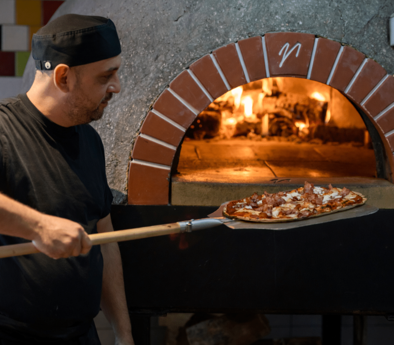 Chef preparing pizza from wooden oven